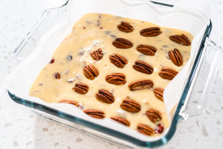 Pouring fudge mixture into the baking pan lined with parchment paper to prepare white chocolate...