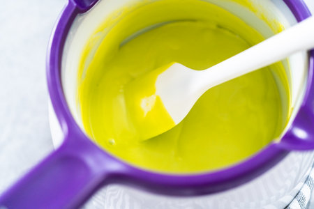 Melting color chocolate chips in a candy melting pot to make carrot chocolate-covered pretzels.の写真素材