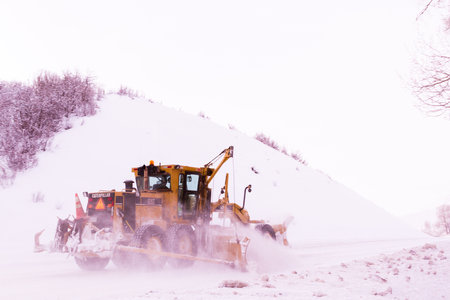 Yellow snowplow clearing rural road from snow.のeditorial素材