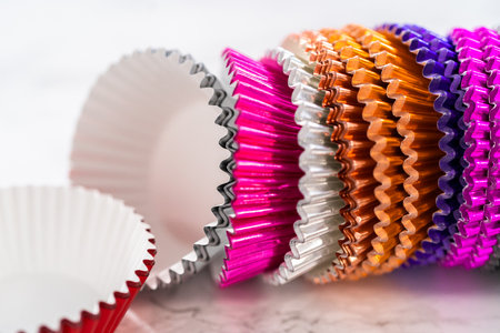 Close-up view. Multicolor foil lining cups for cupcakes on a marble countertop.の写真素材