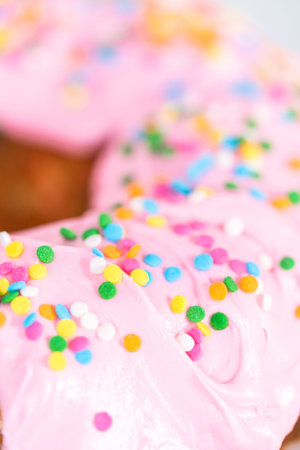 Close up view. Sliced funfettti bundt cake with pink buttercream frosting on top and buttercream...