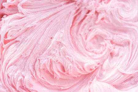 Close up view. Mixing in pink food coloring into a vanilla buttercream frosting for decorating funfettti bundt cake.の写真素材