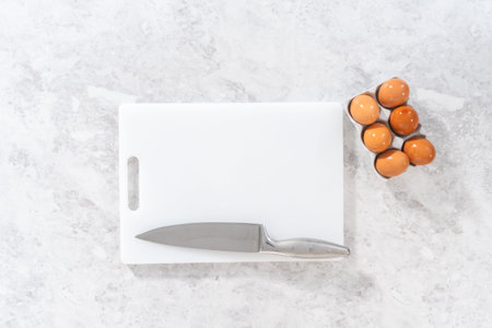 Flat lay. Cutting hard-boiled eggs on a white cutting board.の写真素材
