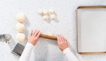 Flat lay. Rolling bread dough with a french rolling pin to bake naan dippers.