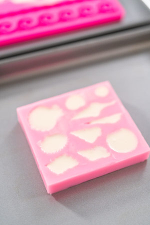 Filling silicone chocolate molds with white melted chocolate to prepare mermaid cakesicles.の写真素材