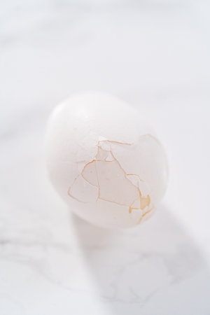 Peeling hard-boiled eggs at the marble kitchen counter.の写真素材