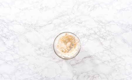 Flat lay. Mixing in store-bought buttercream frosting in a glass mixing bowl.の写真素材