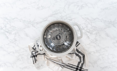 Flat lay. Steaming fresh broccoli in a cooking pot with a steamer basket to prepare steamed...