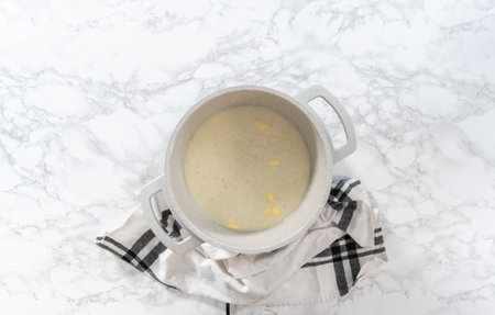 Flat lay. Cooking cheesy sauce in a cooking pot to prepare macaroni and cheese with broccoli.の写真素材