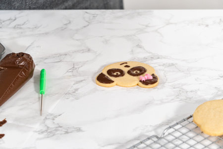 Icing panda-shaped shortbread cookies with chocolate icing.