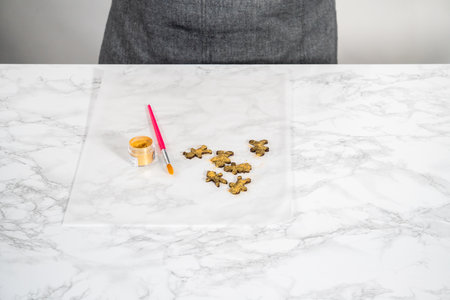 Dusting chocolate ginger man with food golden dust for cake toppers.の写真素材