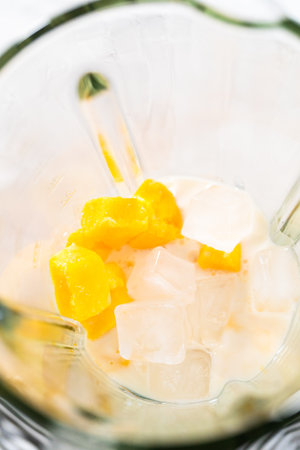 Mixing ingredients in kitchen blender to prepare mango boba smoothie.の写真素材