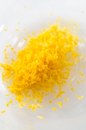 Zesting and juicing fresh lemon on a white cutting board.の写真素材