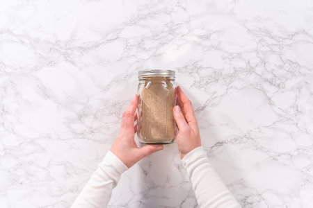 Flat lay. Dry yeast in a glass mason jar on the marble surfaceの写真素材