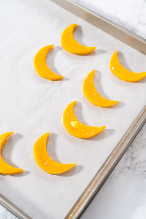 Lemon wedge cookies with lemon glaze. Rolling cookie dough with an adjustable rolling pin and cutting out cookies with cookie cutters to bake lemon wedge cookies with lemon glaze.の写真素材