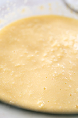Mixing ingredients in a large glass mixing bowl to bake apple bundt cake with caramel glaze.の写真素材