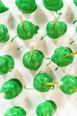 Dipping dough balls into green melted chocolate to make cactus cake pops for the Cinco de Mayo celebration.の写真素材