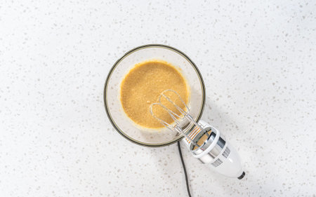 Flat lay. Mixing ingredients with a hand mixer in a large mixing bowl to bake dulce de leche...