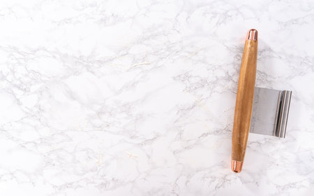 Flat lay. Rolling pizza dough with a french rolling pin to prepare cinnamon dessert pizza.の写真素材