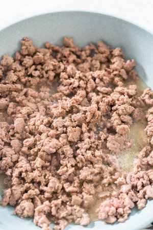 Browning ground turkey on a nonstick frying pan to bake turkey empanadas.の写真素材