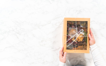Flat lay. Charcuterie box featuring sliced meat, cheese, crackers, and grapes, all neatly packaged...