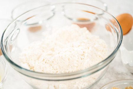 Measured ingredients in glass mixing bowls to bake eggnog scones.