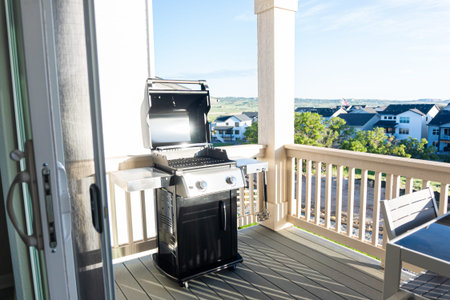 Sleek, open-lid, two-burner grill stands ready for use, conveniently positioned on the balcony of a...