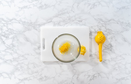 Zesting and juicing fresh lemon on a white cutting board.の写真素材