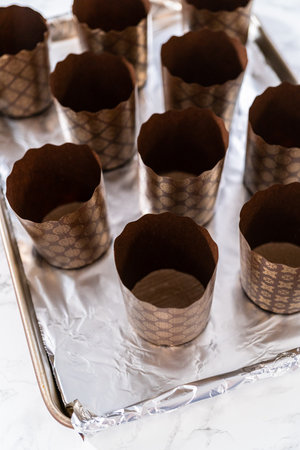Scooping bread dough into paper liners to bake mini Easter bread kulich.の写真素材