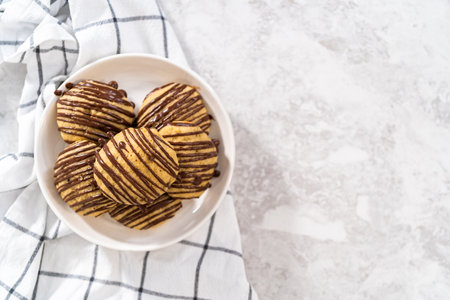 Freshly baked banana cookies with chocolate drizzle on a white ceramic plate.の写真素材