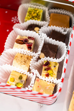 Packaging a homemade variety of fudge for Christmas food gifts into tin boxes.の写真素材