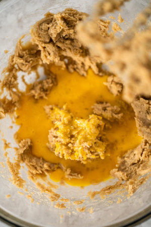 Mixing ingredients in a large glass mixing bowl with a kitchen mixer to bake chocolate cookies with...