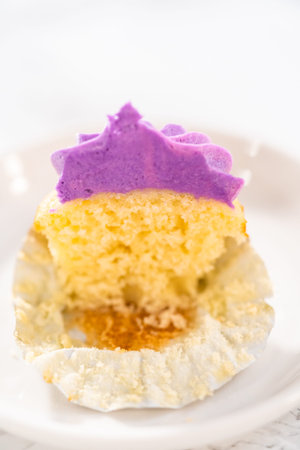 Sliced freshly baked mini vanilla cupcakes with ombre pink buttercream frosting on a white plate.