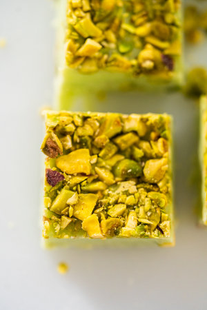 Homemade pistachio fudge pieces on a white cutting board.の写真素材