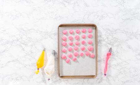 Piping meringue from the piping bags with the metal tip into parchment paper to bake meringue...