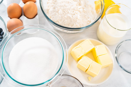 Measured ingredients in glass mixing bowls to bake lemon blueberry bundt cake.の写真素材