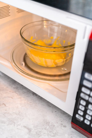 Melting yellow chocolate chips in a glass mixing bowl in a microwave.