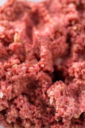 Mixing ingredients with hands in a glass mixing bowl to make meatloaf.の写真素材