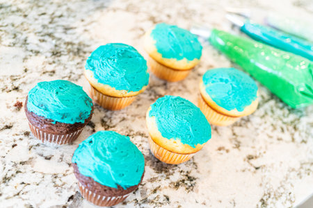 Using buttercream frosting, vanilla and chocolate cupcakes are intricately decorated to resemble...
