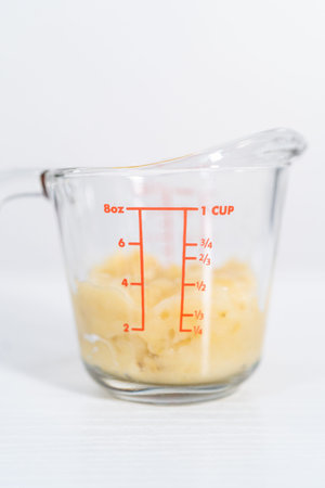 Mashed ripe banana in a glass measuring cup.