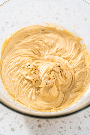 Mixing ingredients with a hand mixer in a large mixing bowl to bake dulce de leche cupcakes.