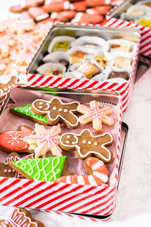 Packaging a homemade variety of fudge and gingerbread cookies for Christmas food gifts into tin boxes.の写真素材