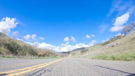 Vehicle is cruising along the Cuyama Highway under the bright sun. The surrounding landscape is illuminated by the radiant sunshine, creating a picturesque and inviting scene as the car travels through this captivating area.の写真素材