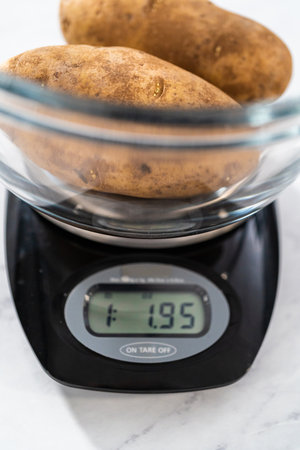 Pressure Cooker Baked Potatoes. Measuring raw potatoes in a glass mixing bowl on the kitchen scale.の写真素材
