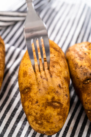 Pressure Cooker Baked Potatoes. Poking raw potatoes with a fork to prepare baked potatoes.の写真素材