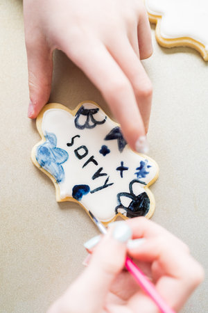 A heartwarming scene of a little girl carefully writing Sorry on sugar cookies with food coloring, the cookies beautifully flooded with white royal icing.の写真素材