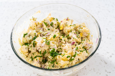 Mixing ingredients in a large glass mixing bowl to make potato salad.の写真素材