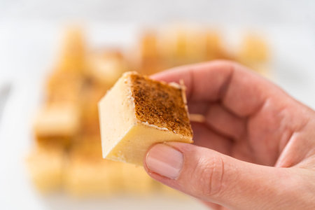 Homemade eggnog fudge pieces on a white cutting board.