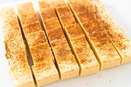 Homemade eggnog fudge pieces on a white cutting board.の写真素材