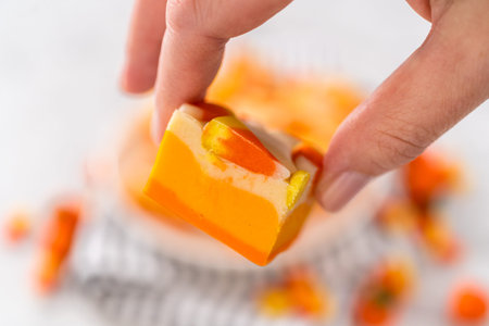 Homemade candy corn fudge square pieces on a white plate.